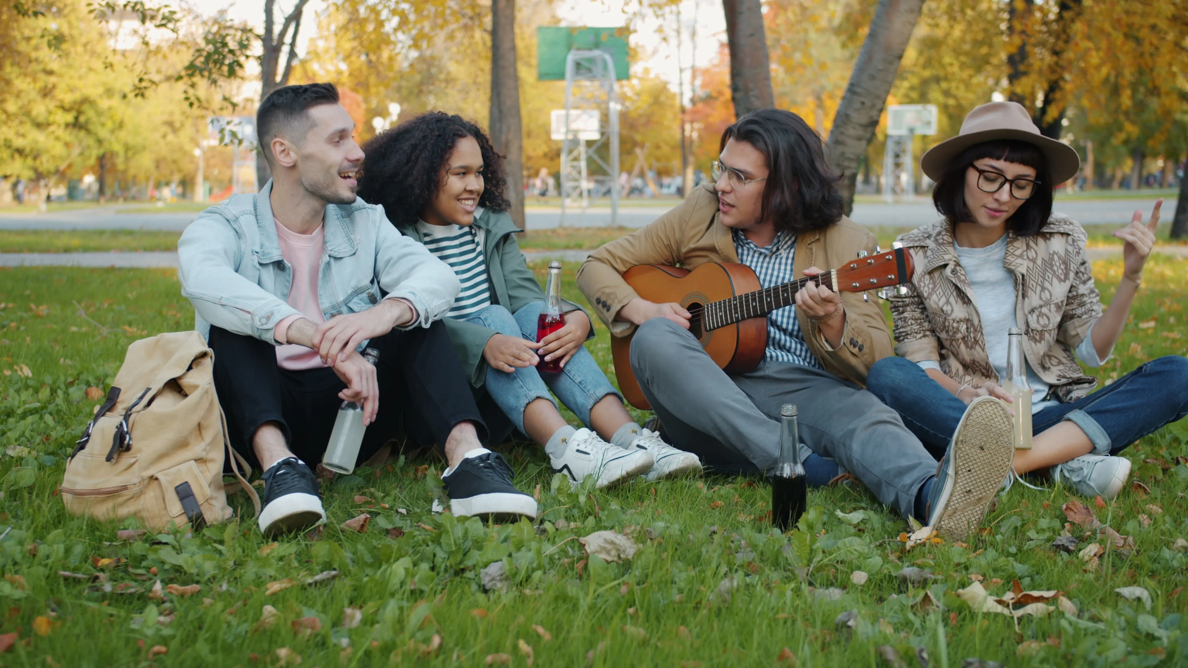 Gen Z friends sitting on grass in a park laughing and playing guitar — real connection and authentic relationships are the antidote to porn's isolation